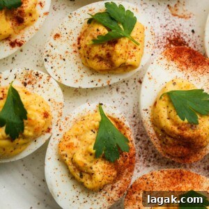 Deviled eggs topped with parsley and sprinkled with paprika and black pepper.