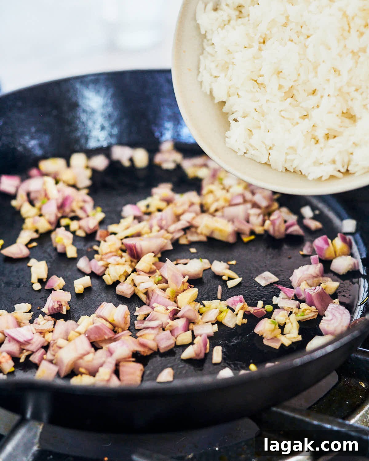 Sautéed shallots and garlic in a skillet, adding rice for Thai Green Curry Fried Rice. 