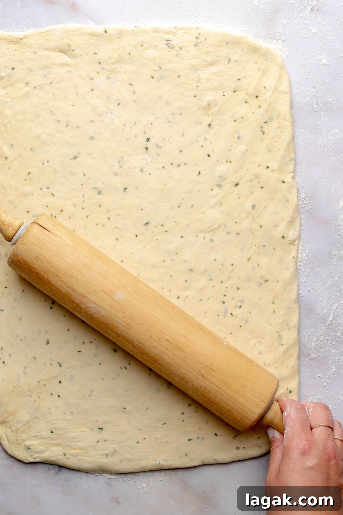 Savory Breakfast Rolls with Creamy Hollandaise Sauce 11 A rolling pin rolls out savory cinnamon roll dough in a rectangle.