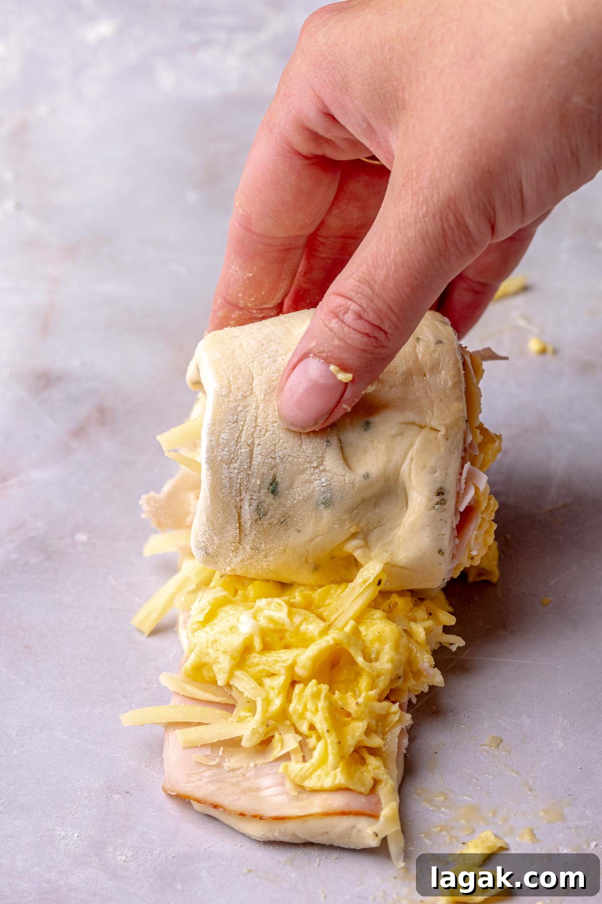 Savory Breakfast Rolls with Creamy Hollandaise Sauce 13 A hand rolls up a strip of savory cinnamon roll dough.