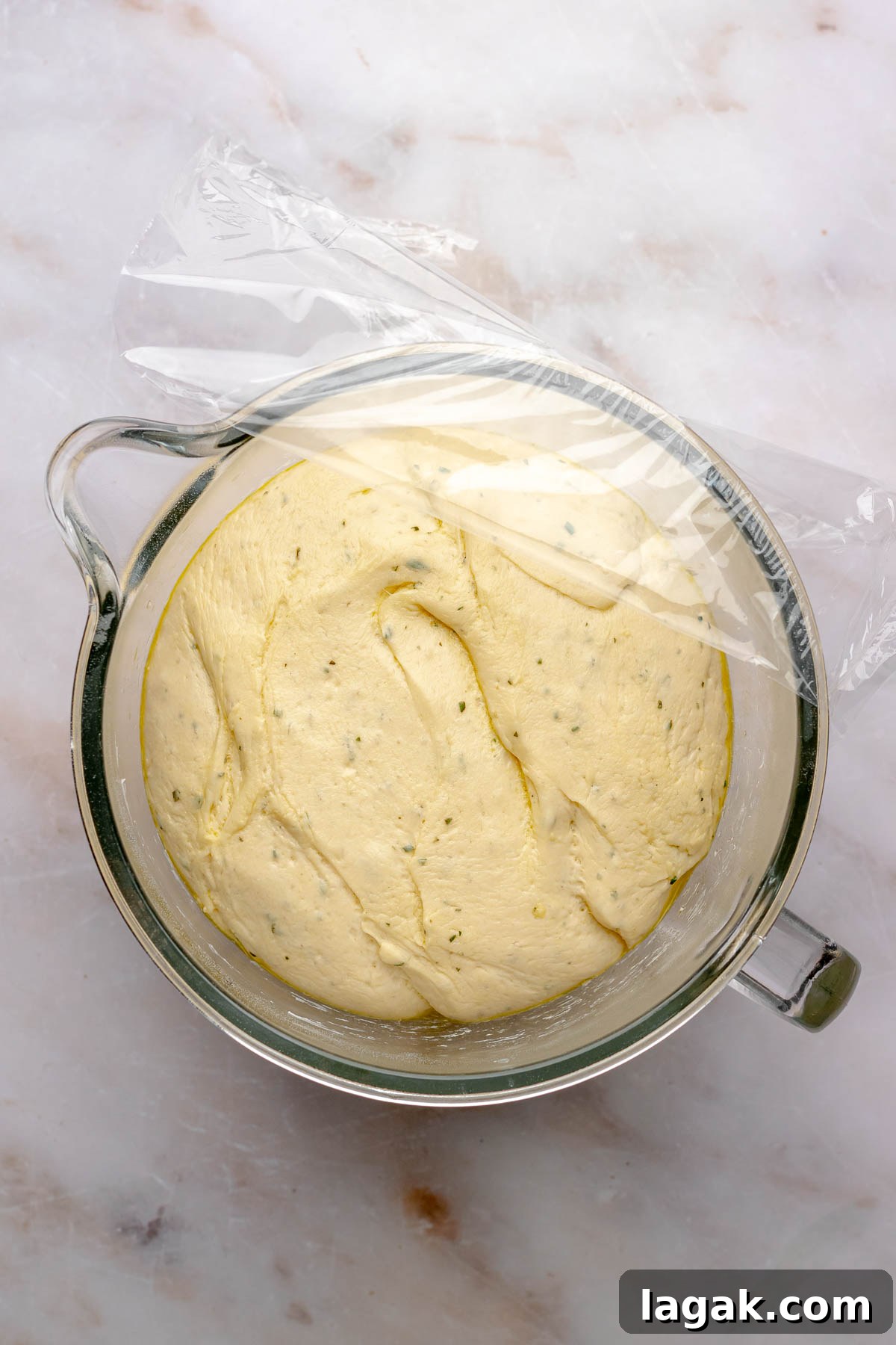 Savory Breakfast Rolls with Creamy Hollandaise Sauce 10 Risen herb dough in a bowl with plastic wrap on the side.