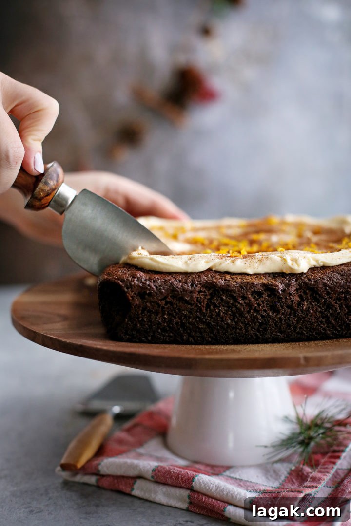 Easy Chocolate Gingerbread Cake Recipe www.goodlifeeats.com woman slicing a chocolate gingerbread cake