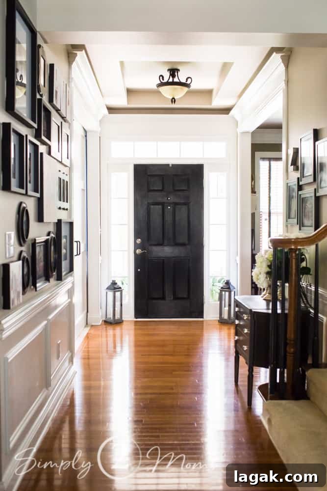 front entry hallway with gallery walls, painted black door, lanterns, and entry table