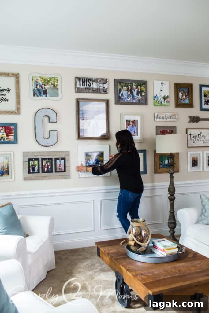 woman adjusting picture frame on wall with gallery wall display on entire wall