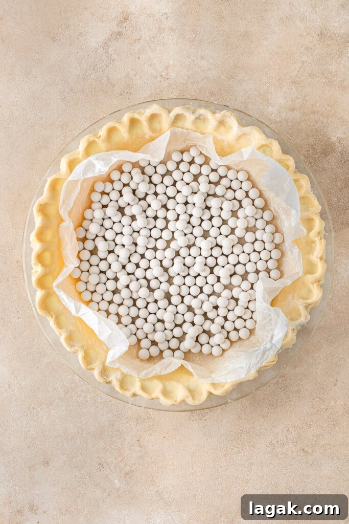 Creamy Dairy-Free Pumpkin Pie Recipe for Fall Celebrations 5 Adding pie weights to the dish.