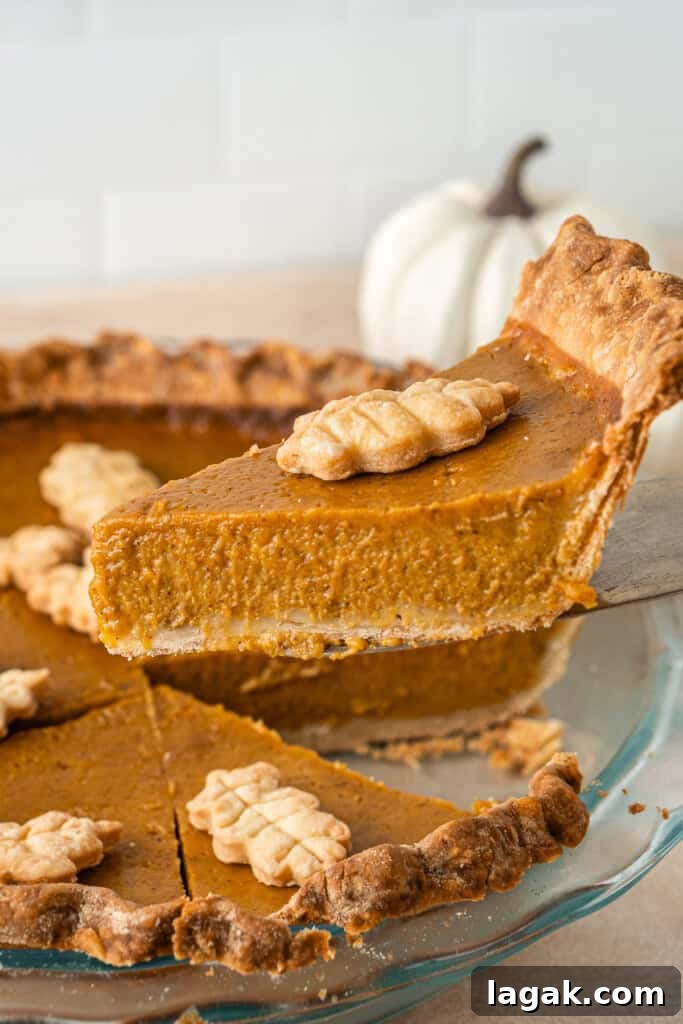 Creamy Dairy-Free Pumpkin Pie Recipe for Fall Celebrations 10 Lifting a slice of pumpkin pie from the dish.