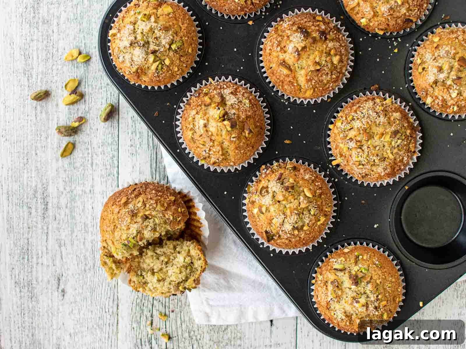 Moist Pistachio Muffins with Lemon Glaze 8 Baked muffins in a muffin pan with one removed to the side and broken in half.