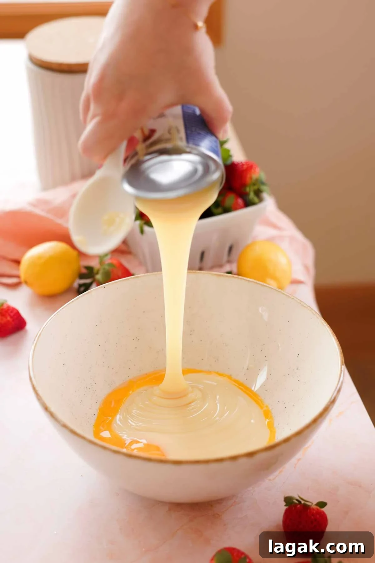 Strawberry Lemon Bars Recipe with Zesty Shortbread Crust 10 adding sweetened condensed milk into a large bowl with egg yolks