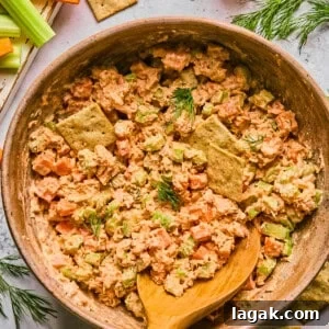High-Protein Buffalo Tuna Salad Recipe for Meal Prep 14 buffalo tuna salad in a pink bowl with a wooden spoon surrounded by crackers and ingredients