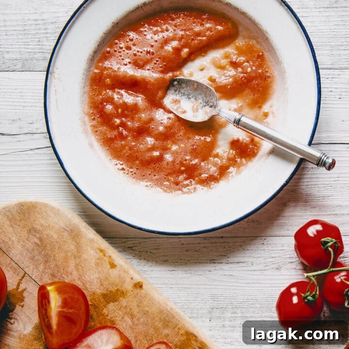 Strapatsada (Kagianas): Classic Greek Tomato Scrambled Eggs Recipe 5 Fresh tomatoes being grated into a bowl to prepare the base for Greek strapatsada.