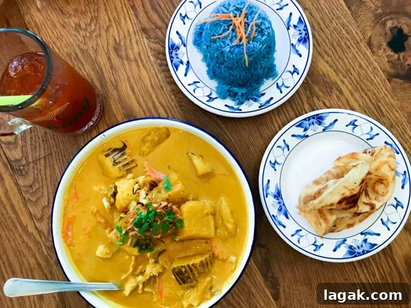 Top Portland Lunch Spots for Spring & Summer 2022 14 Thai Farmhouse Kitchen lunch menu items yellow curry with potato, onion, crispy shallot and chicken with a side of roti and blue rice