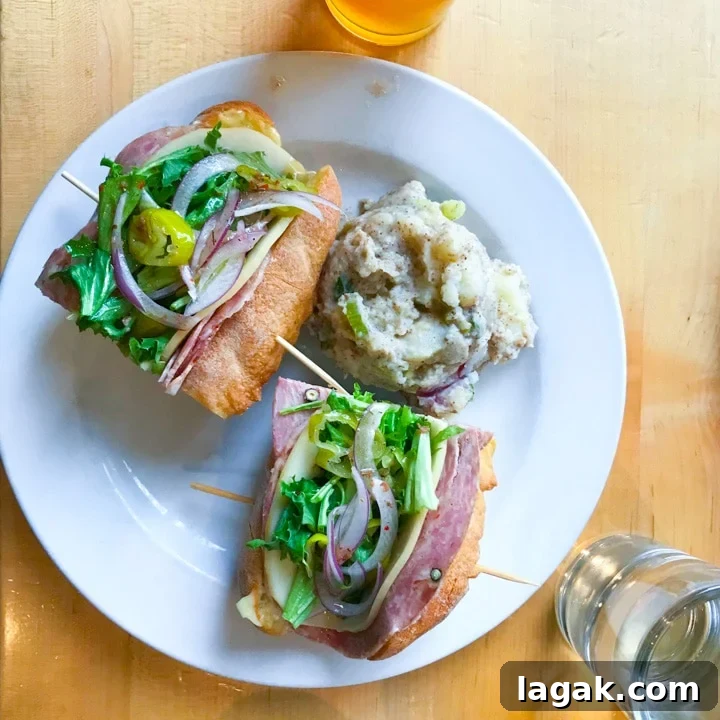 Top Portland Lunch Spots for Spring & Summer 2022 7 olympia provisions lunch menu item italian sandwich on a table with beer in portland