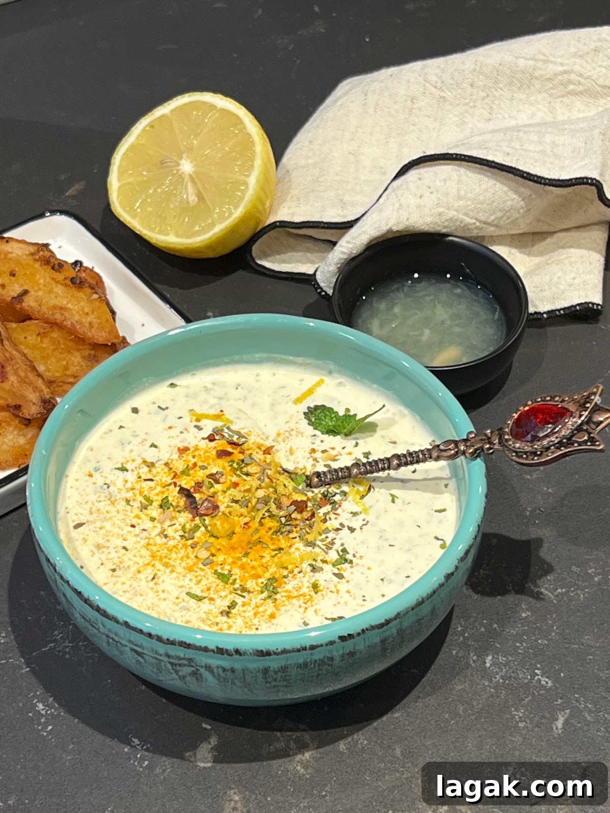 Close up of yogurt mint sauce with a fancy spoon tucked in.