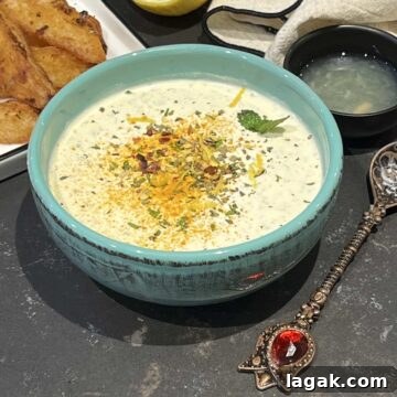 Yoghurt mint sauce in a green serving bowl and spices sprinkled over.