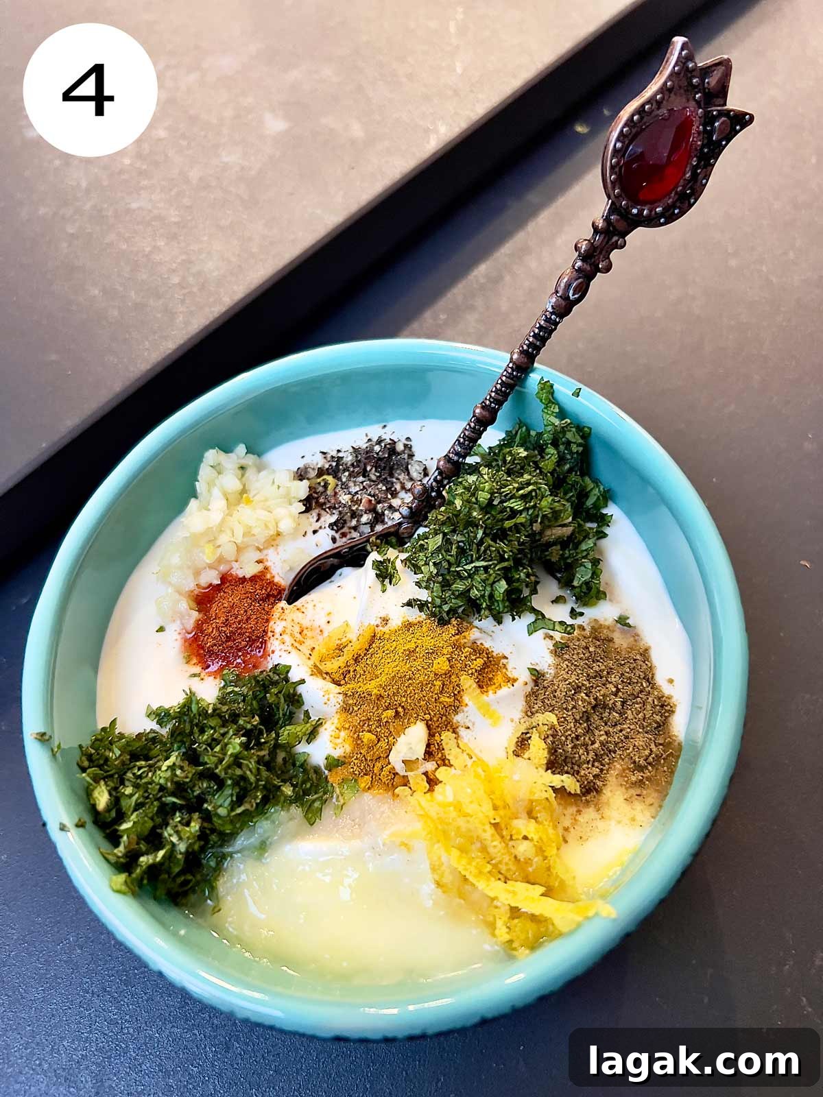 All the ingredients added to the yogurt in a green serving bowl with a teaspoon tucked in.