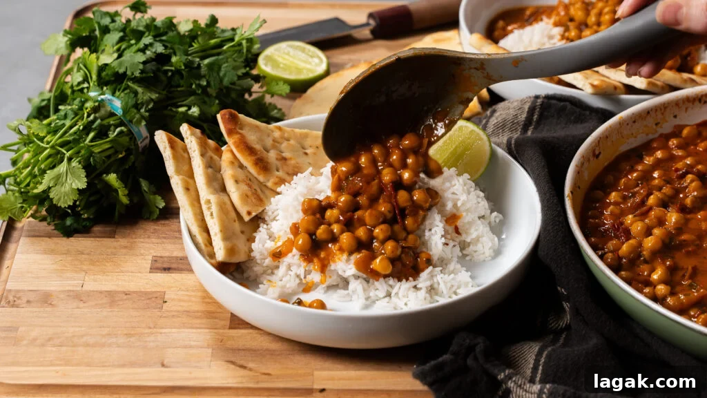 Smoky Creamy One-Pan Chickpea and Rice Skillet Recipe 3 Chickpeas and rice being spooned into a bowl with naan bread on the side.