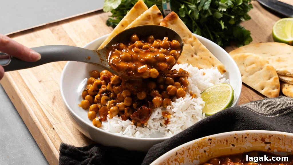 Smoky Creamy One-Pan Chickpea and Rice Skillet Recipe 8 Spooning a chickpeas and rice recipe into a white bowl.