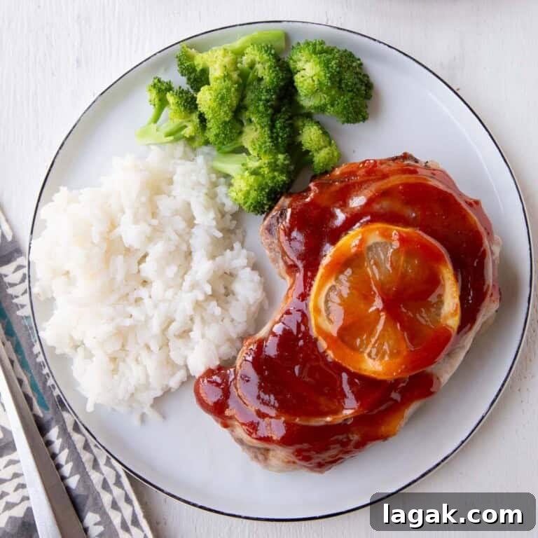 pork chop covered in red sweet and sour sauce with rice and broccoli.