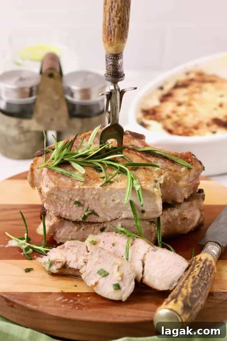 2 pork chops on a cutting board with slices removed and rosemary on top.