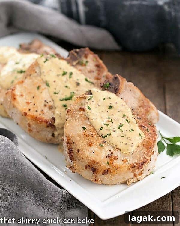 3 pork chops covered with dijonnaise sauce on a white platter.