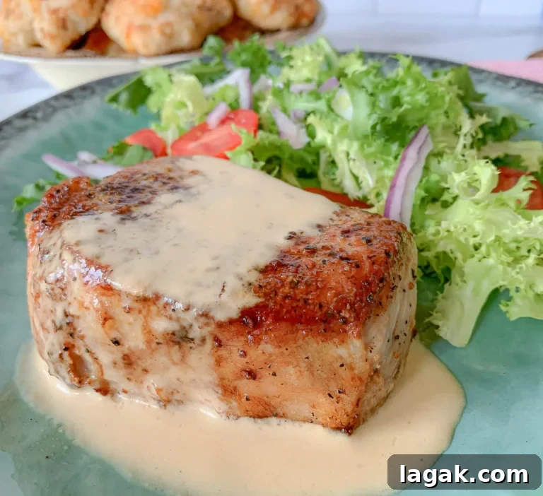 a seared pork chop with au jus sauce and a salad.