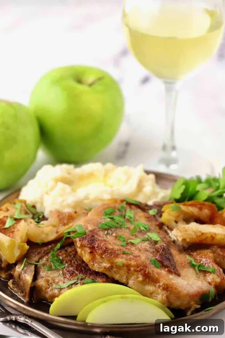pork chops with apples on a plate next to a scoop of mashed potatoes.