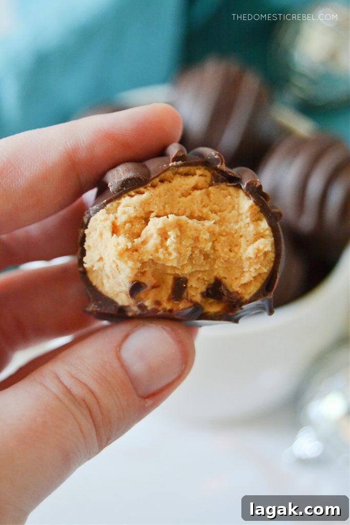 No-Bake Peanut Butter Balls Recipe for Quick Homemade Treats 3 author holding a peanut butter ball truffle with a bite missing to show texture on the inside of the truffle