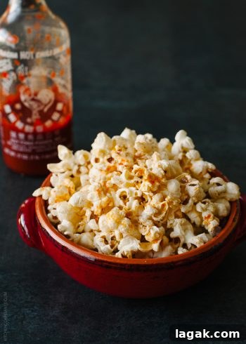 Sriracha-Spiced Popcorn Recipe for Bold, Crunchy Flavor 2 A red bowl filled with spicy sriracha popcorn.