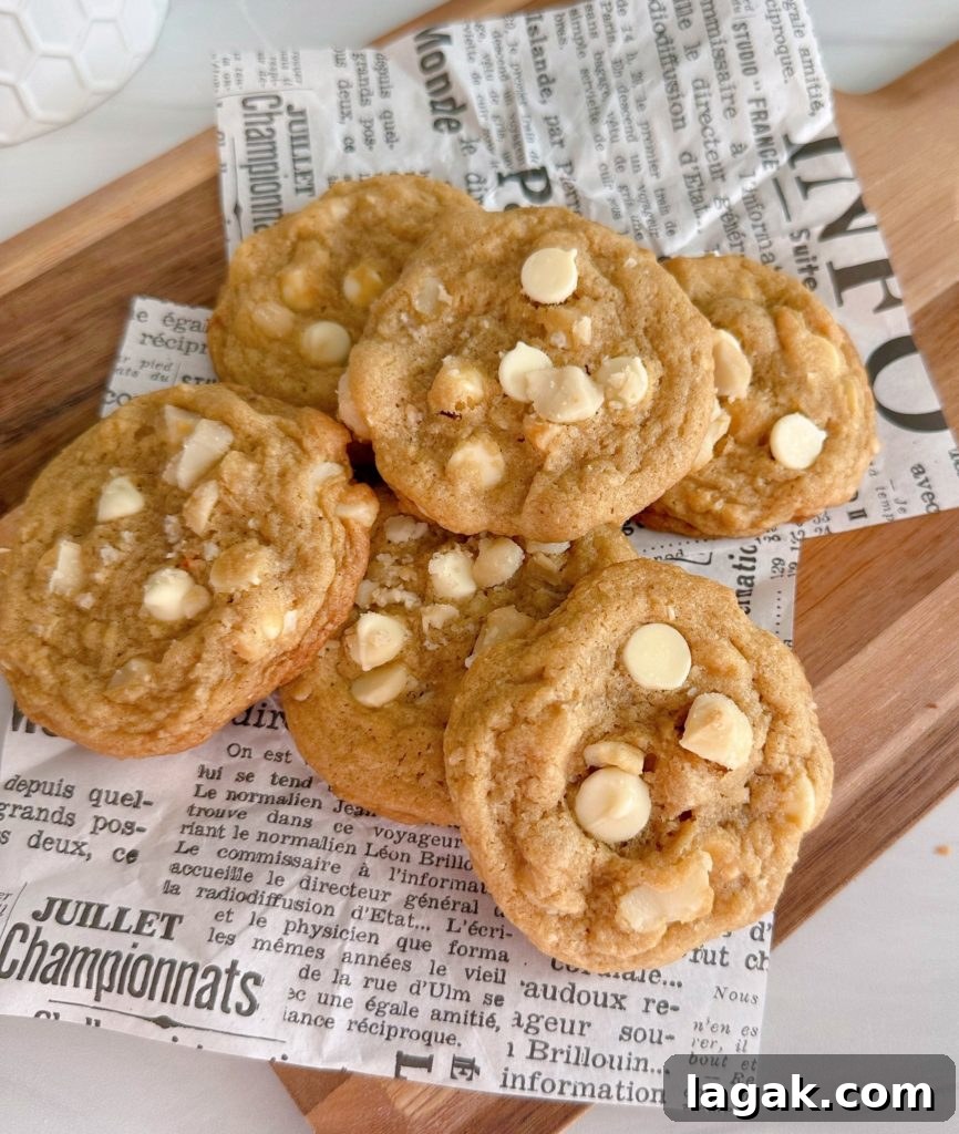 White Chocolate Macadamia Pudding Cookies Recipe 2 Pile of White Chocolate Chip Macadamia Nut Cookies on a cutting board.