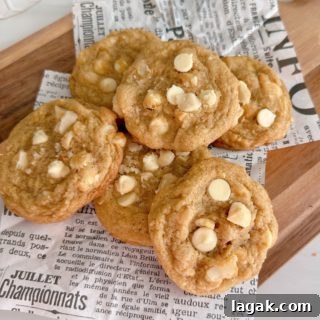 White Chocolate Macadamia Pudding Cookies Recipe 11 Pile of White Chocolate Chip Macadamia Nut Cookies on a cutting board.