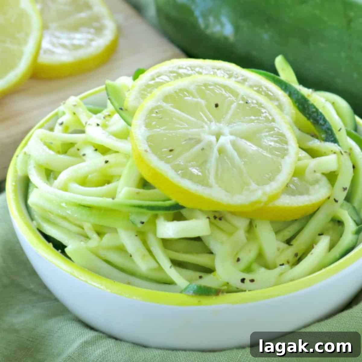 Lemon garlic zucchini noodles in a bowl with lemon slices on top