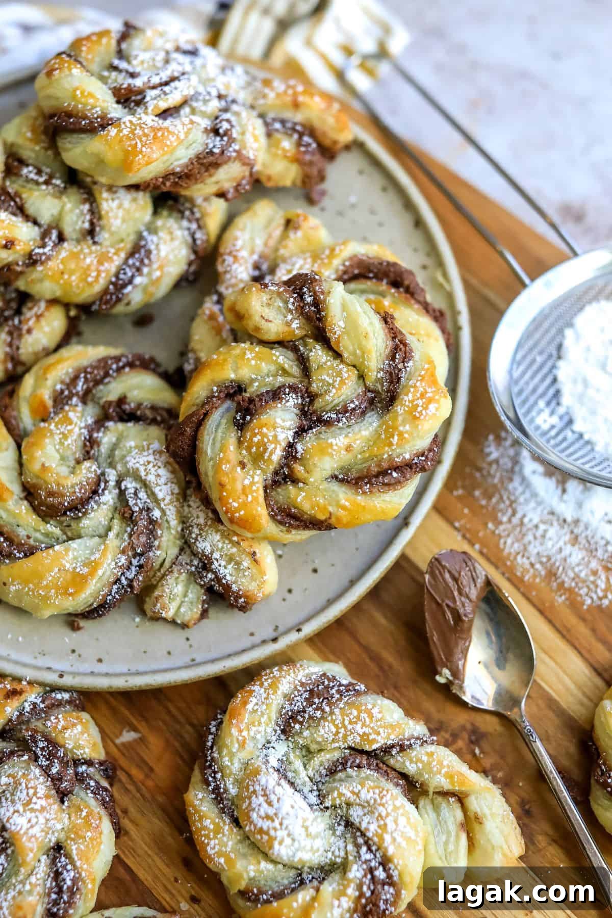 Pastries with Nutella swirled in them on a plate. Powdered sugar on the side.