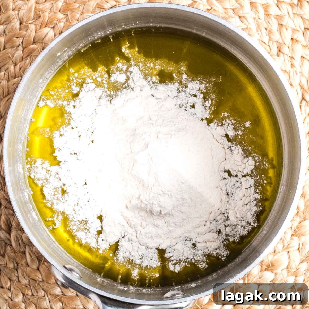 Flour sprinkled on top of olive oil in a small saucepan.