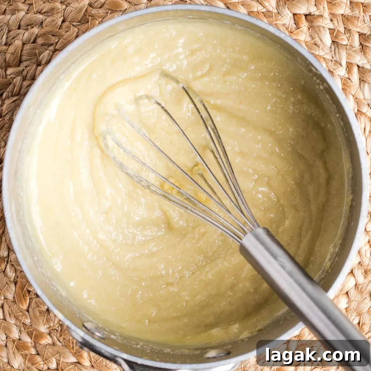 Whisking a pale yellow sauce in a small pot.