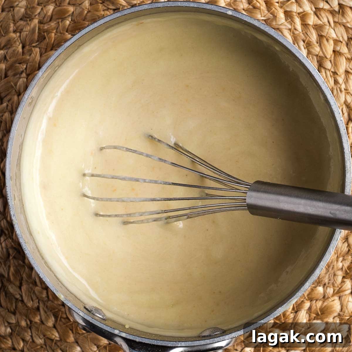Whisking a thick beige sauce in a small saucepan.