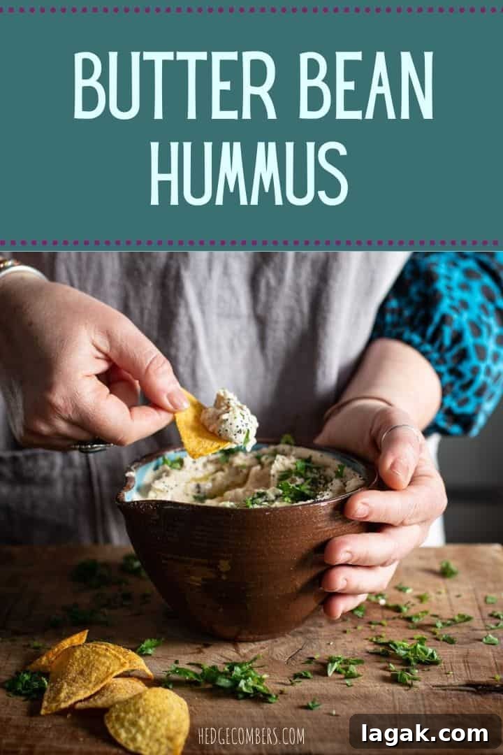 Creamy Vegan Butter Bean Dip — Protein-Packed Snack Recipe 2 Woman's hands scooping butter bean dip from a brown bowl on a wooden kitchen counter