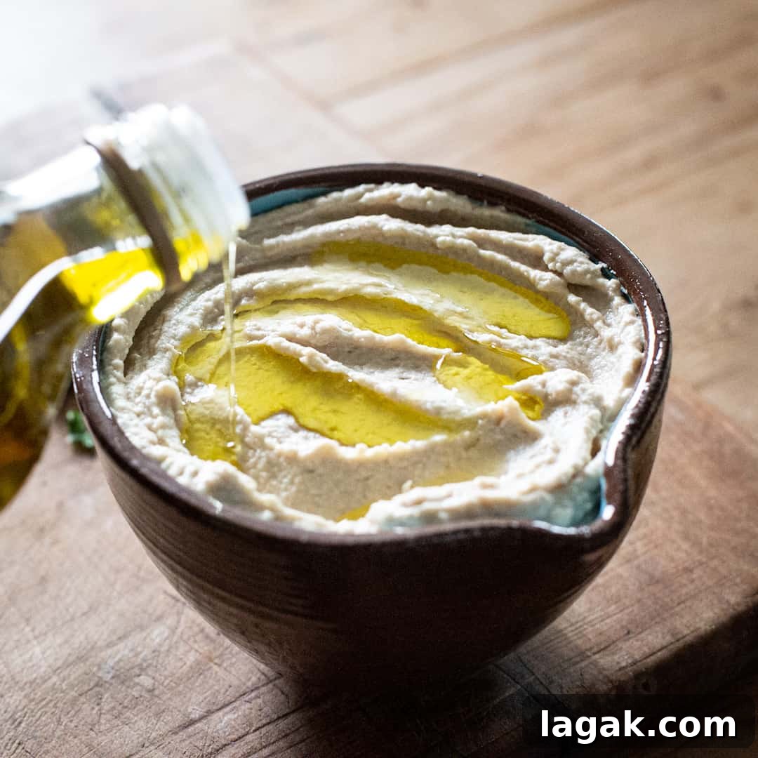 Creamy Vegan Butter Bean Dip — Protein-Packed Snack Recipe 12 Bowl of butter bean hummus being topped with olive oil