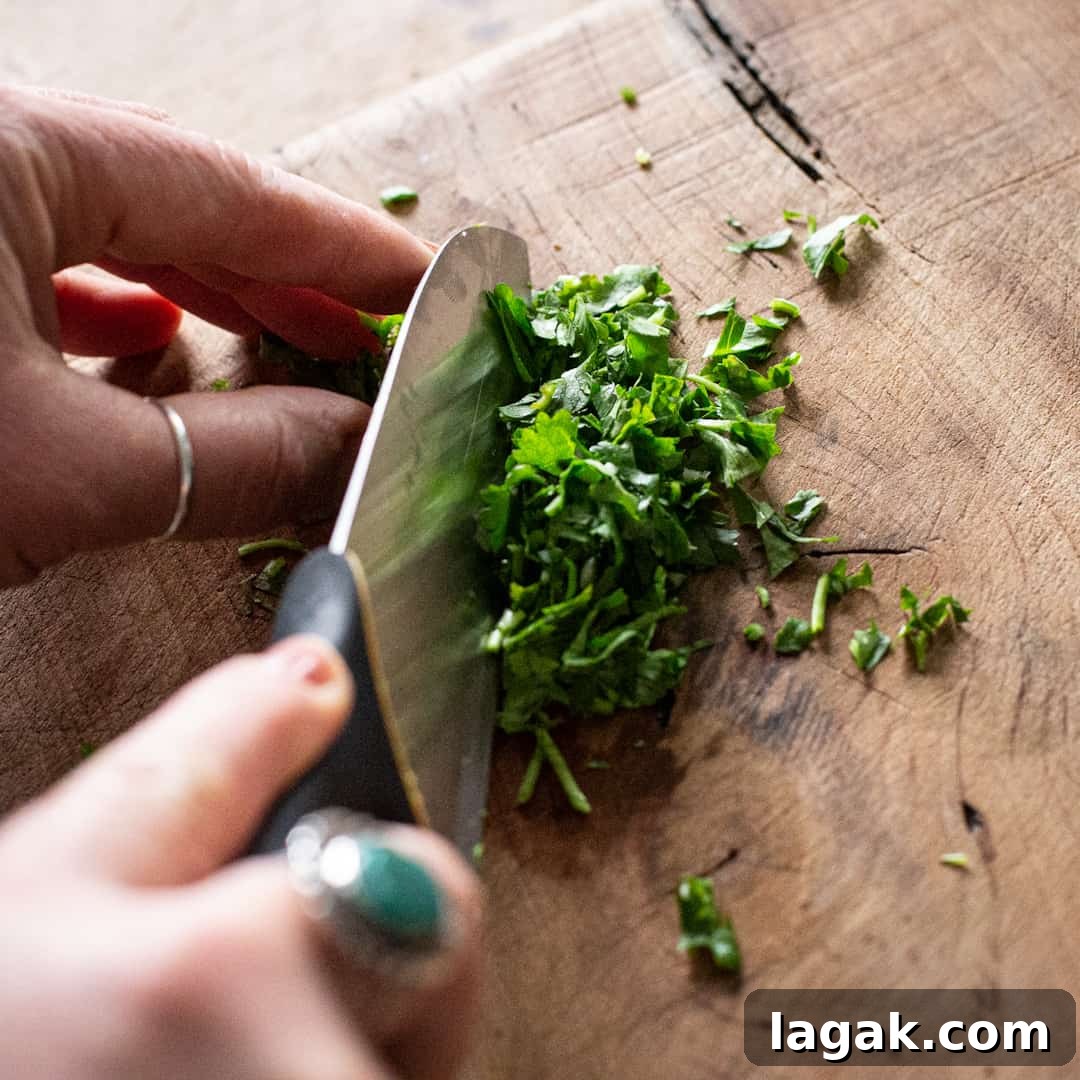 Creamy Vegan Butter Bean Dip — Protein-Packed Snack Recipe 13 Chopping fresh parsley on a wooden chopping board