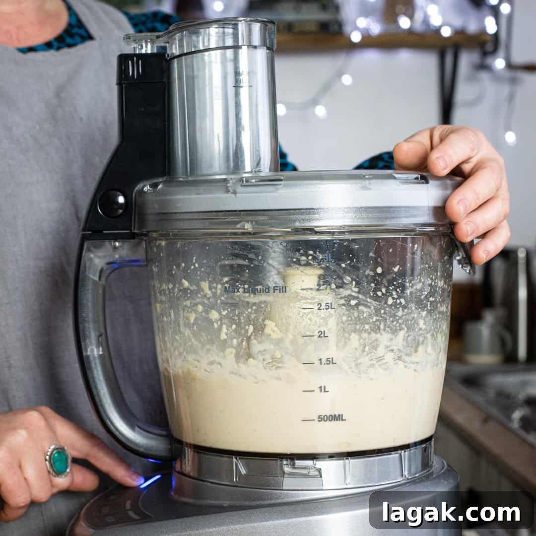 Creamy Vegan Butter Bean Dip — Protein-Packed Snack Recipe 9 Mixing cooked beans in a silver food processor to make hummus