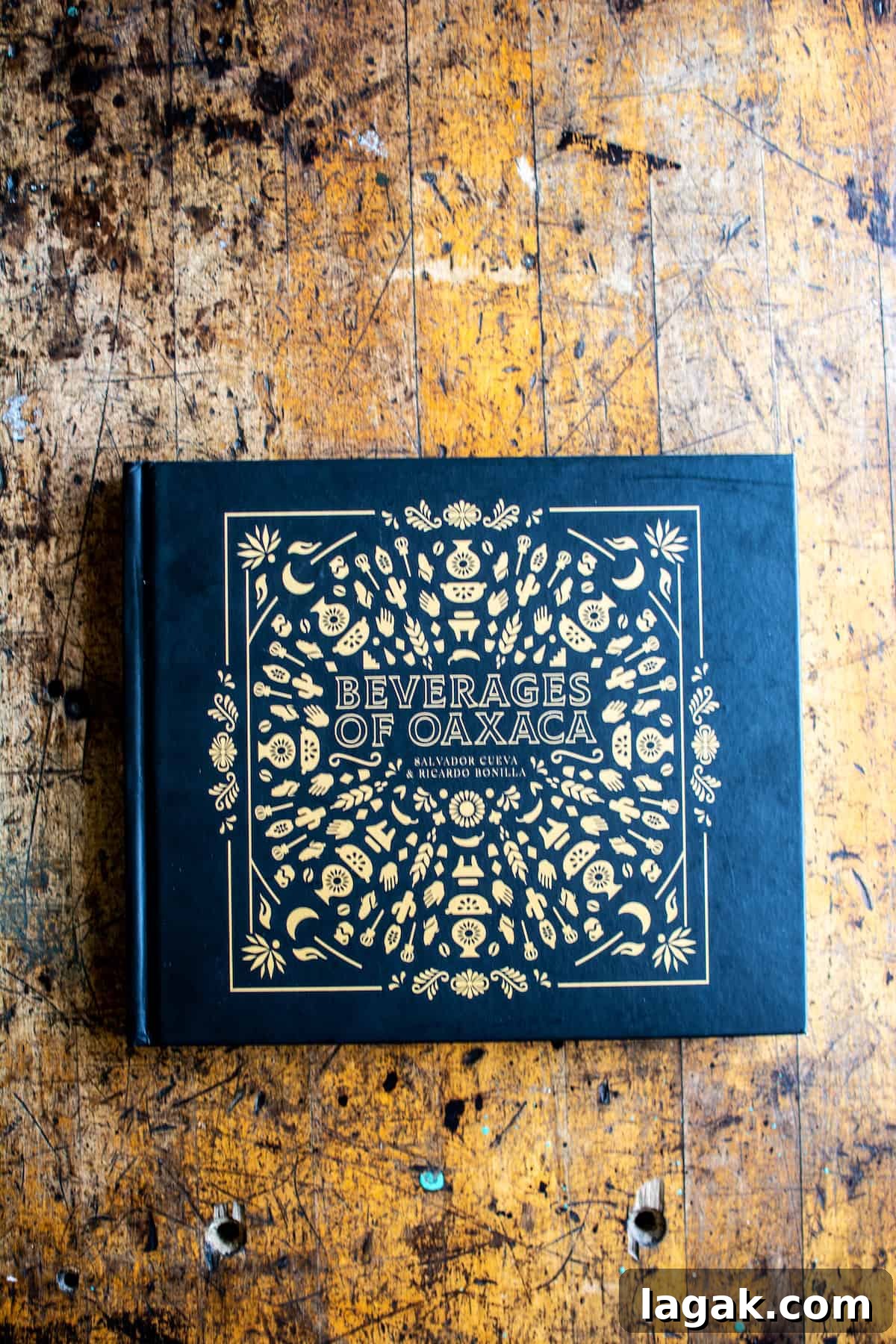 Vegan Atole: Warm Cinnamon Corn Drink Recipe 3 A black book with gold lettering and design sitting on a wood table. The title of the book is Beverages of Oaxaca by Salvador Cueva and Ricardo Bonilla.