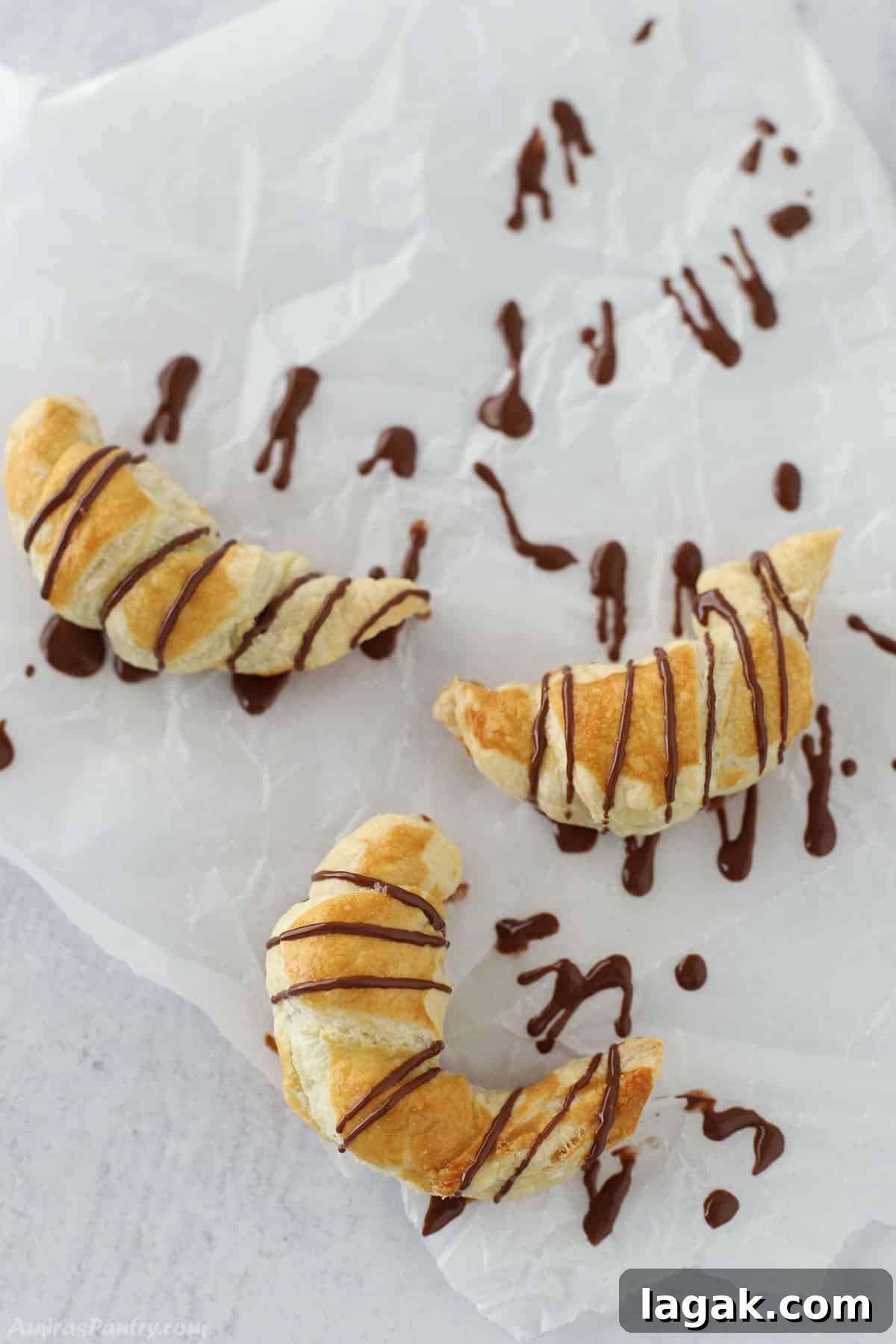 How to Make Classic Chocolate Croissants (Pain au Chocolat) 2 Chocolate croissants on a parchment paper.