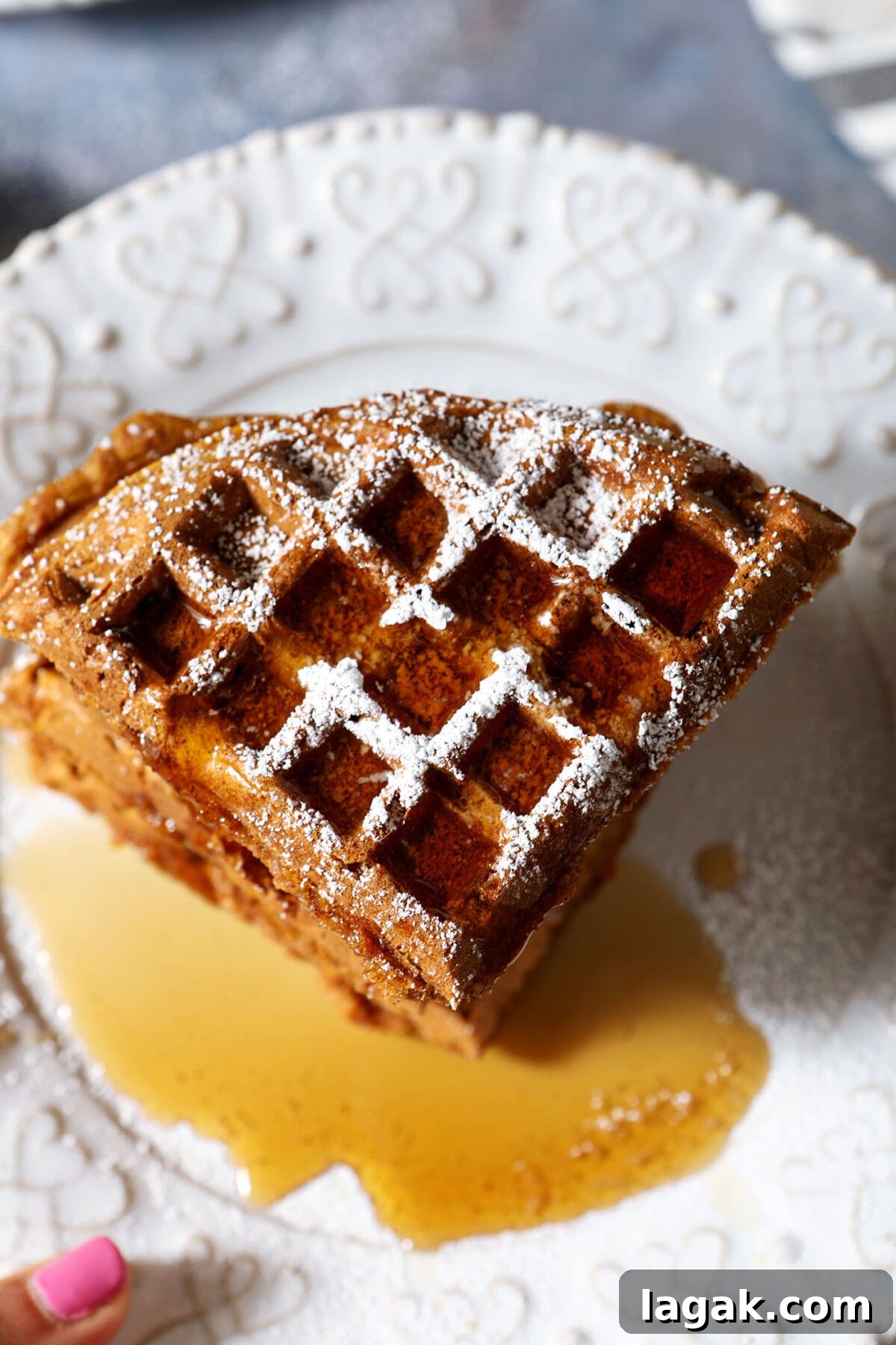 Pumpkin Waffles with Cinnamon Maple Syrup Recipe 11 Overhead of a stack of pumpkin waffles topped with powdered sugar and maple syrup