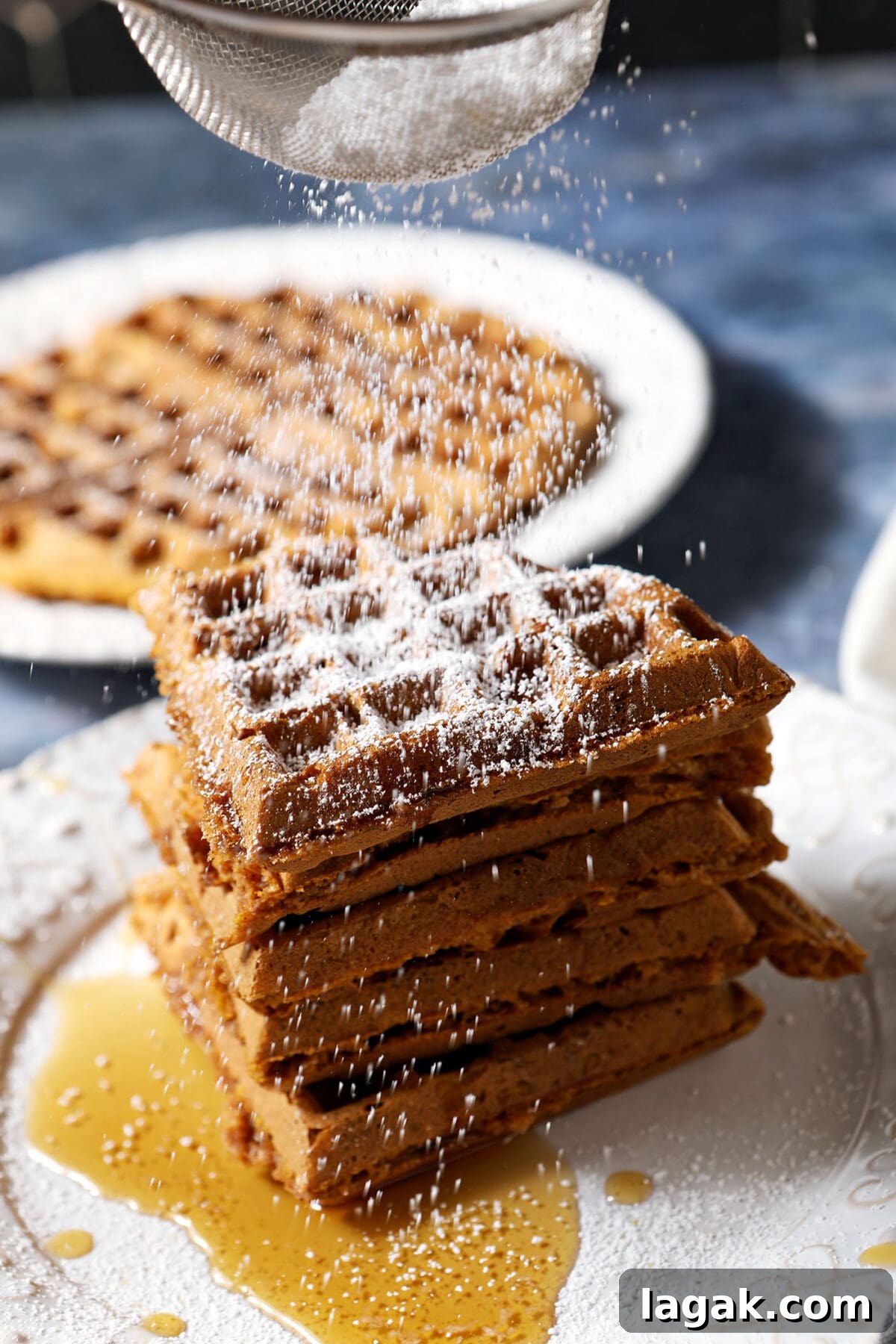 Pumpkin Waffles with Cinnamon Maple Syrup Recipe 10 Powdered sugar sprinkles down on top of a stack of pumpkin waffles