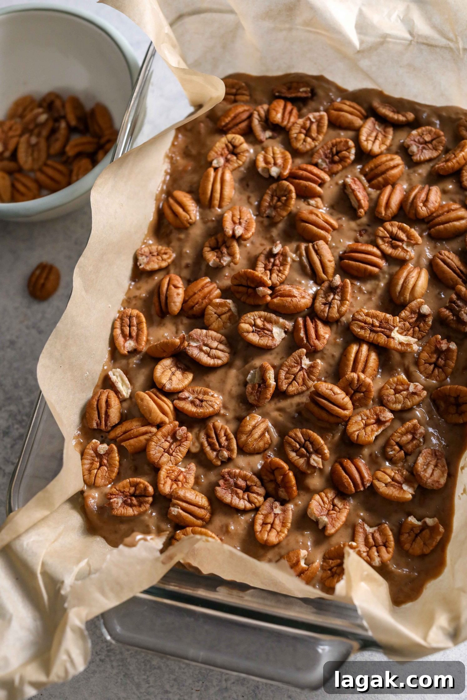 Chewy Pecan Pie Bars with Buttery Shortbread Crust 6 Pecan Pie Bars in parchment lined baking dish topped with pecans by Flora & Vino