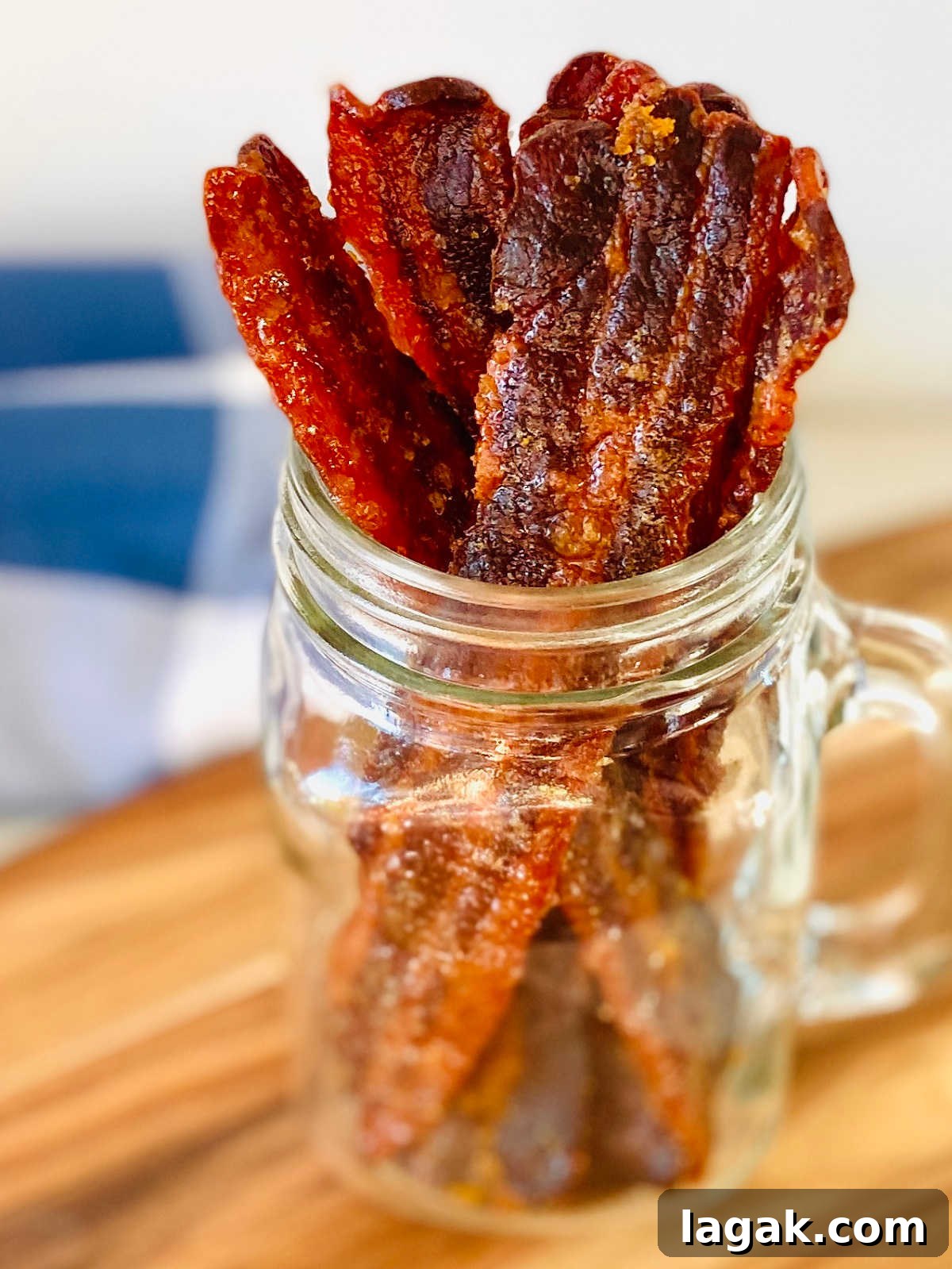 Savory Bacon Jerky: Homemade Recipe and Cooking Tips 5 maple bacon jerky sitting upright in glass jar with blue napkin in background