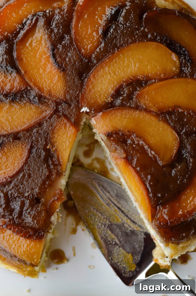 Caramelized Fresh Peach Upside-Down Cake Recipe for Summer 2 A close-up photo a peach upside down cake wit a cake server in the pan.