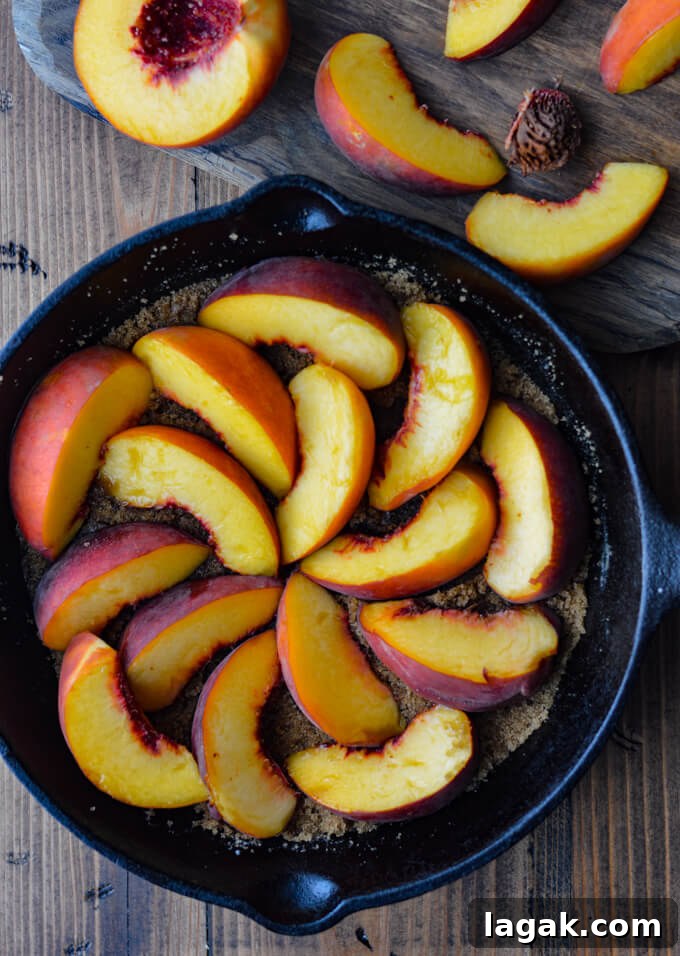 Caramelized Fresh Peach Upside-Down Cake Recipe for Summer 3 A cast iron pan of brown sugar and butter in the bottom with fresh peach slices arrange in a circular motion on top.