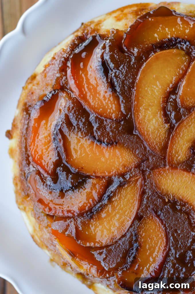 Caramelized Fresh Peach Upside-Down Cake Recipe for Summer 7 A closeup photo of a peach upside down cake on a white platter.