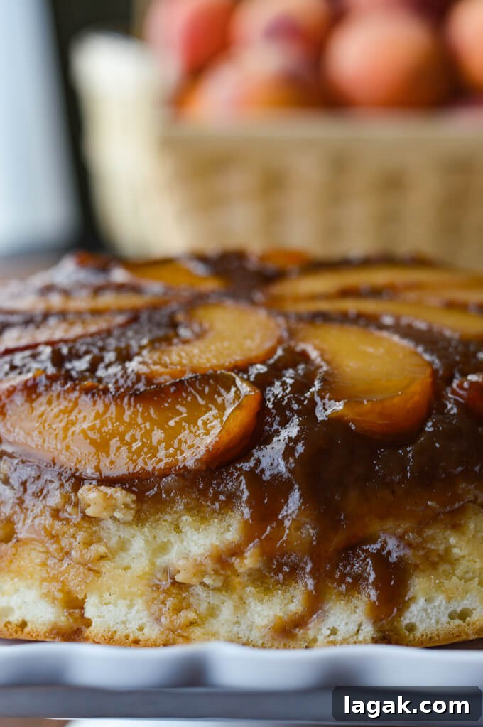 Caramelized Fresh Peach Upside-Down Cake Recipe for Summer 8 A front view of a peach upside down cake with a basket of peaches in the background.