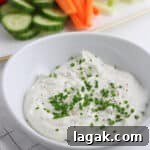 A white bowl of sour cream and chive dip topped with chives.